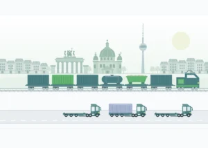 Cargo transfer in front of the Berlin skyline: loaded freight train with container, tank and bulk cargo loads, as well as flatbed trucks on the road.